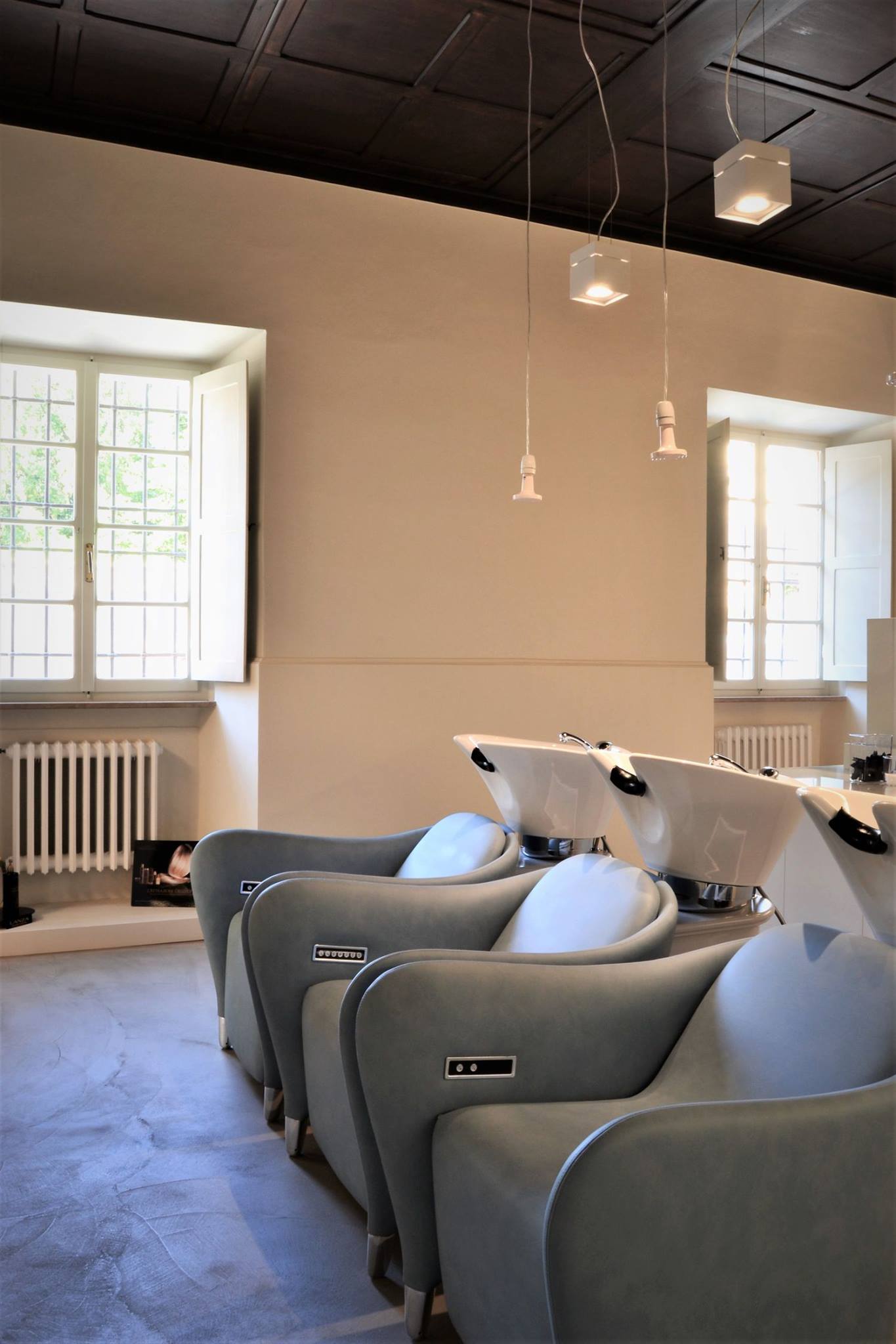 arte e cura del capello • francesco valentini | architetto regione marche - particolare delle poltrone Maletti della zona lavaggio. L'ambiente risulta perfettamente bilanciato: cassettonato in legno a soffitto, superficie continua tipo microcemento a terra ed arredamento sobrio e dai colori pastelli.